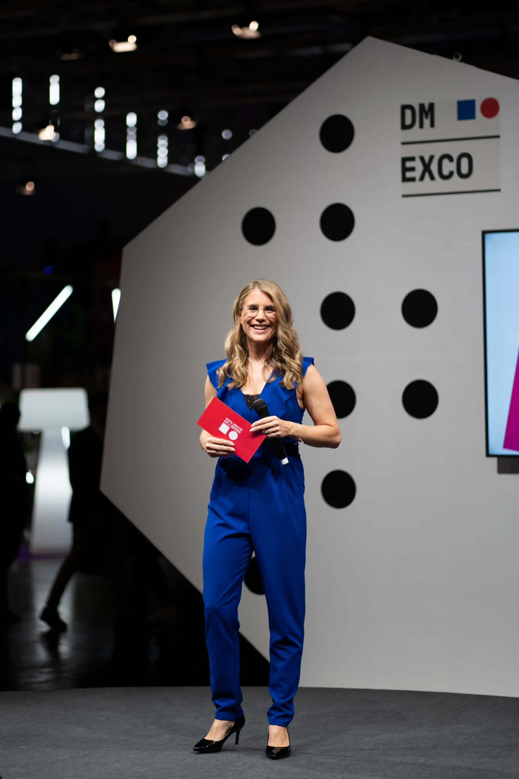 Moderatorin für KI Events Janine Utsch im blauen Jumpsuit auf der Köln Start Up Stage