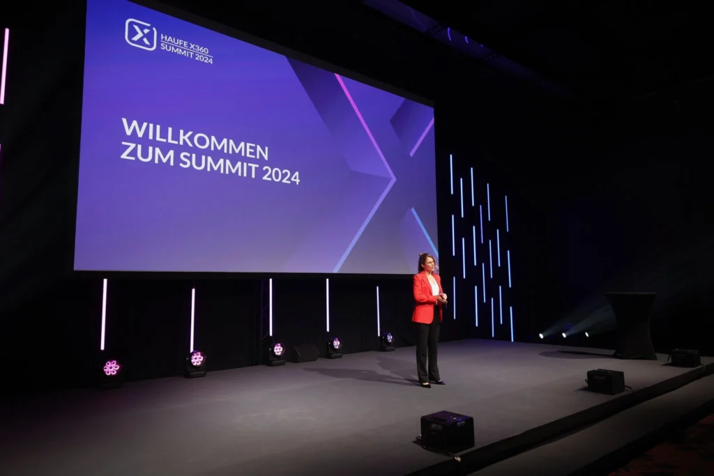 Moderatorin für KI Events Janine Utsch im roten Blazer auf der Bühne des Haufe Summit 2024