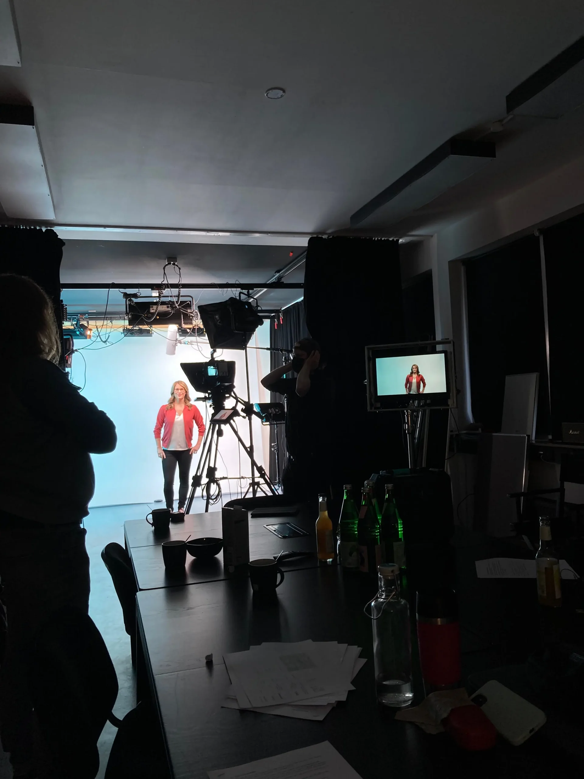 TV Moderatorin Janine Utsch vor einer hellen Wand vor der Kamera stehend, davor zahlreiche Aufnahmetechnik