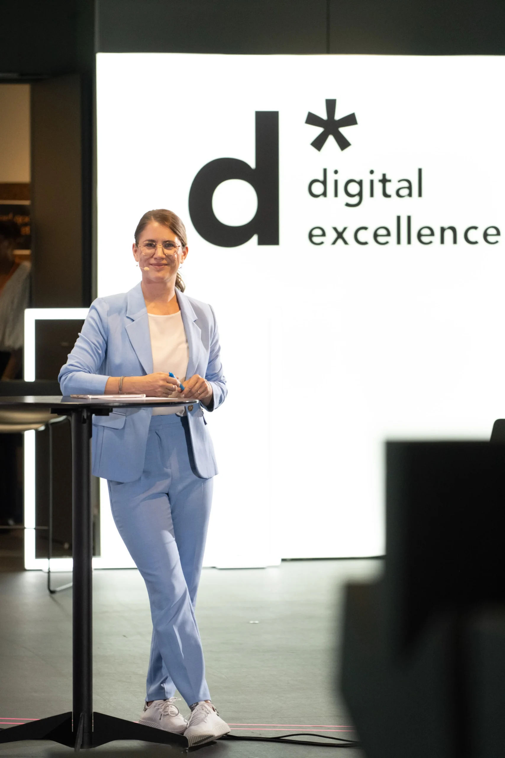 Janine Utsch an einem Stehtisch während einer Moderation in Frankfurt